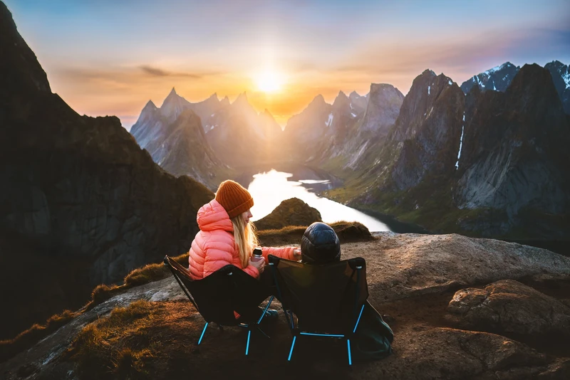 Coppia su sedie da campeggio che guarda il tramonto sulle montagne norvegesi.