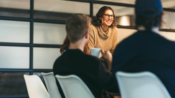 Asesora sonriente hablando con dos clientes en una mesa
