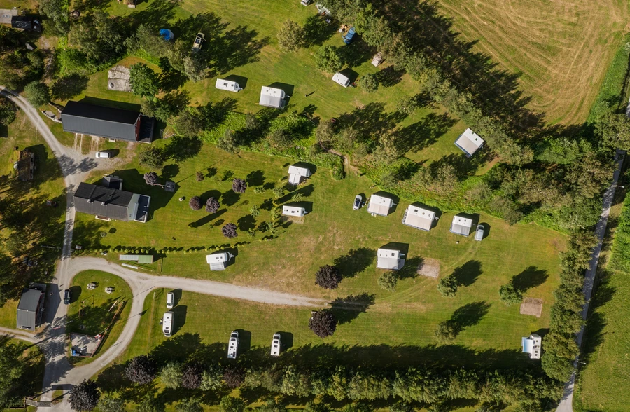 Vue aérienne d’un camping avec des camping-cars et des caravanes parmi les arbres