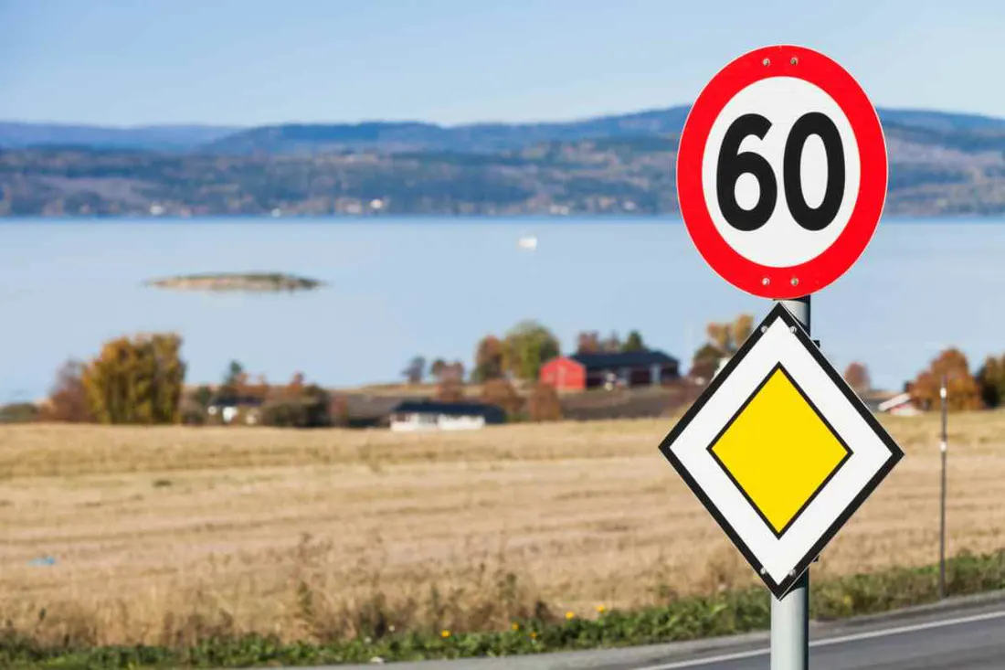 Speed limit and priority road signs beside a fjord in Norway