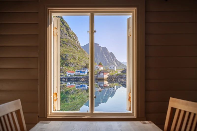 Village au bord d'un fjord vu par la fenêtre d'un chalet en bois