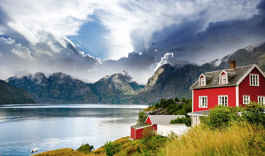 Maison en bois rouge au bord d’un fjord norvégien