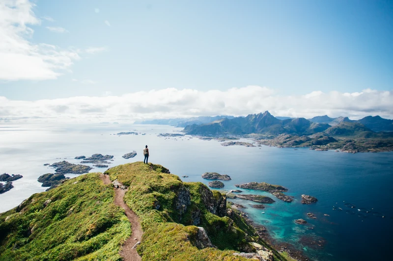 Randonneur sur un promontoire verdoyant face aux îles et à la mer en Norvège