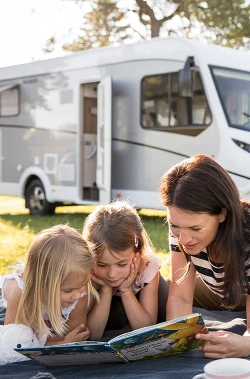 Famille lisant une carte dans l'herbe à côté d'un camping-car