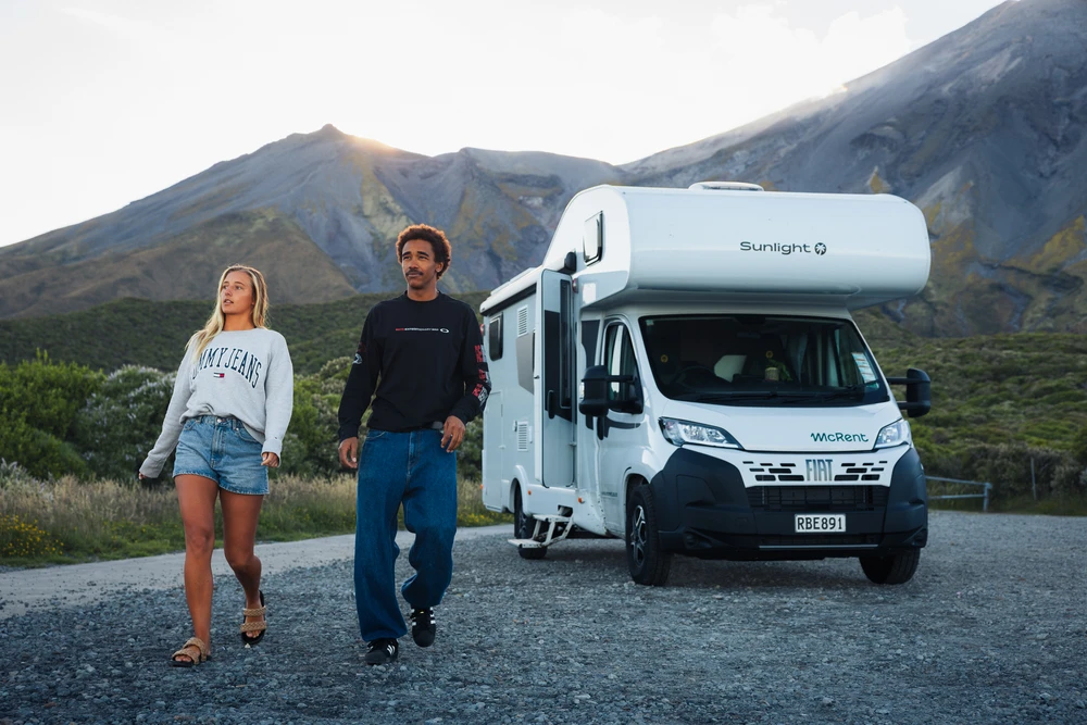 Couple marchant à côté d’un camping-car sur une route de montagne