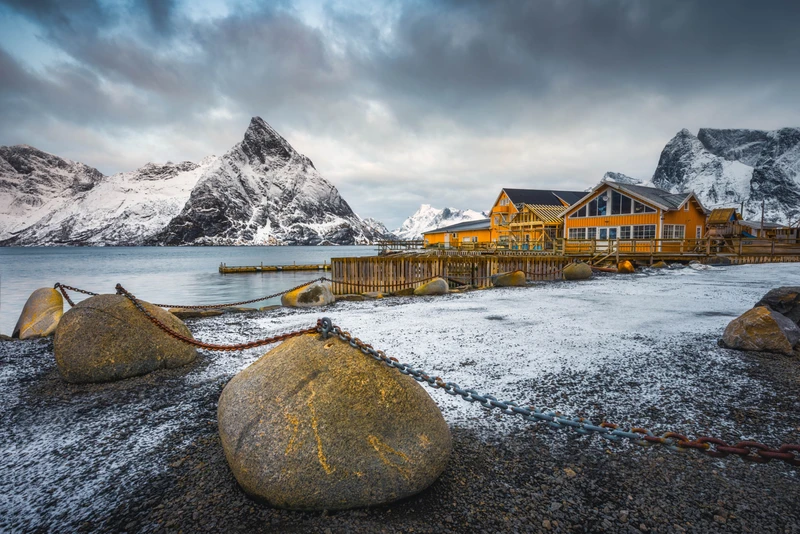 Cabanes en bord de mer au pied de sommets enneigés, dans le nord de la Norvège