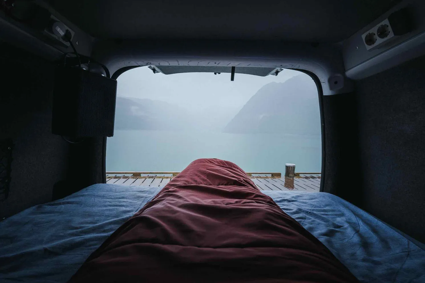 View of a fjord from the bed of a campervan