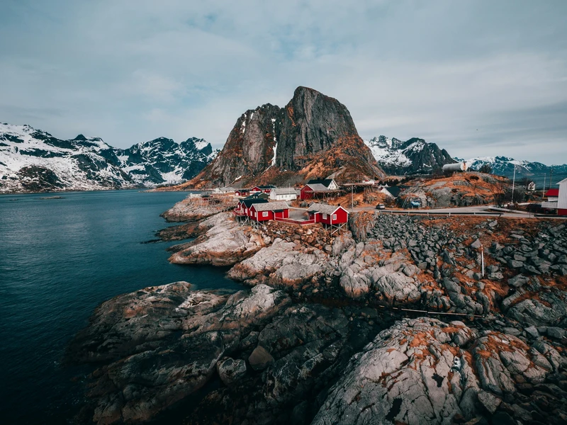 Red fishermen's cabins on the rocks beneath a mountain in Lofoten