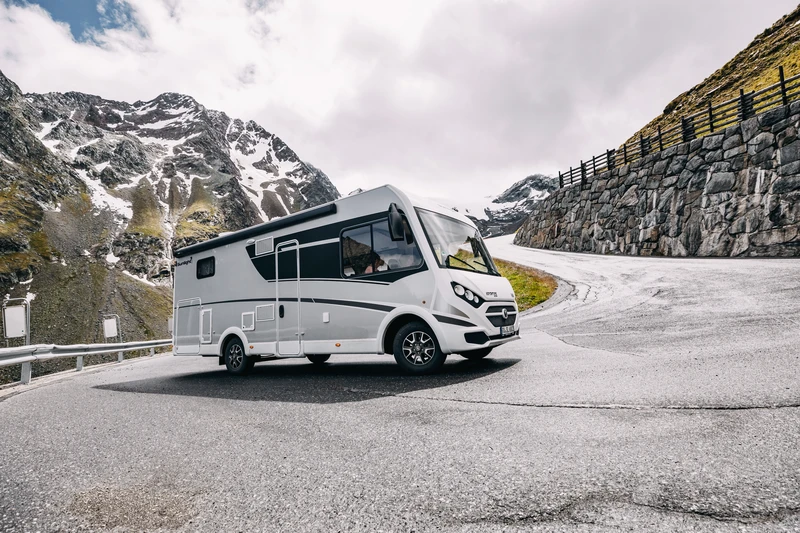 Autocaravana en una carretera de montaña entre cumbres nevadas