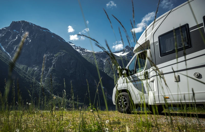 Autocaravana aparcada en un prado al pie de las montañas