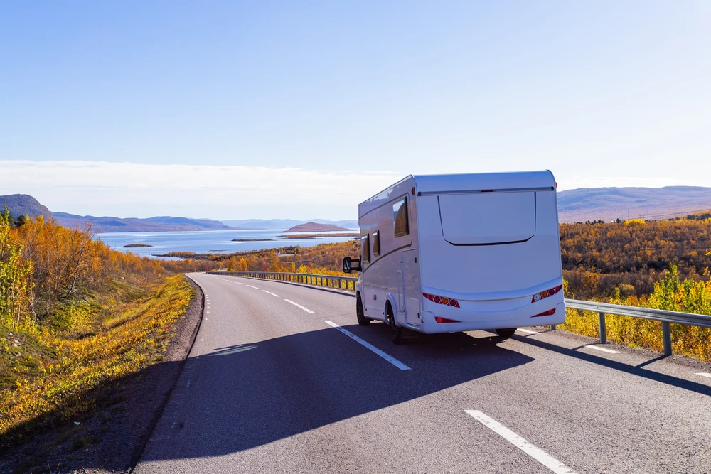 Autocaravana en una carretera costera con colores de otoño